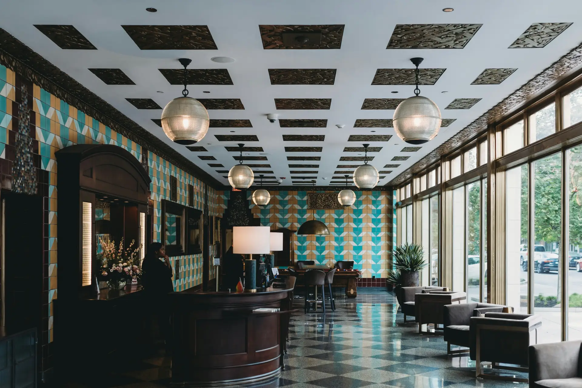 A hotel lobby with a curved reception desk, patterned tilework, and a checkered floor