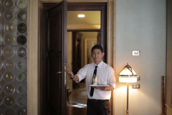 A hotel room-service waiter carrying a tray